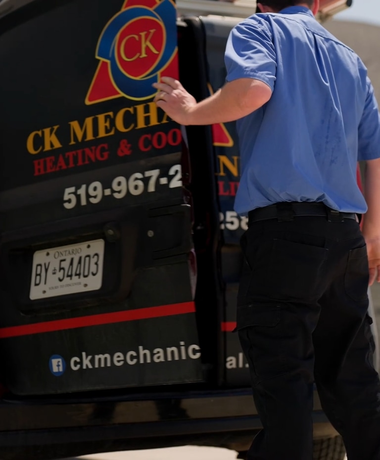 A person in a blue shirt opens the back door of a black CK Mechanical Heating & Cooling van with Ontario plates. Business logo and contact details are visible on the vehicle.